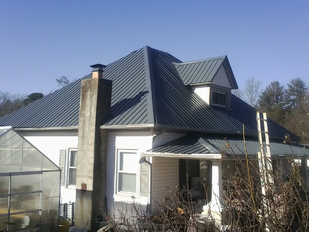Dark blue standing seam metal roof on a white farmhouse with dormer — Slate & Tile Roof Repair by Roofing Brothers in Galway