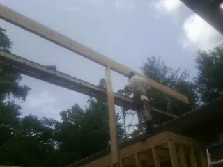 Carpenter setting a ridge beam over a new addition frame — Ice Dam Removal by Roofing Brothers in Galway