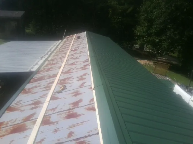 Old rusted panels beside newly installed green metal roofing — Wind Damage Roof Repair by Roofing Brothers in Galway