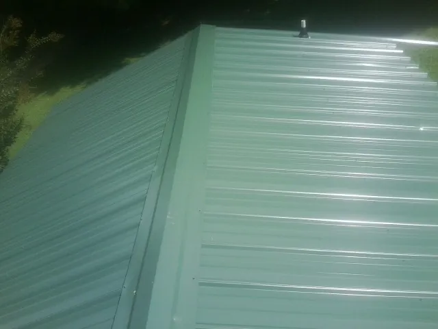New green metal panels meeting at the ridge of a roof — Flat Roof Repair work by our crew in Galway