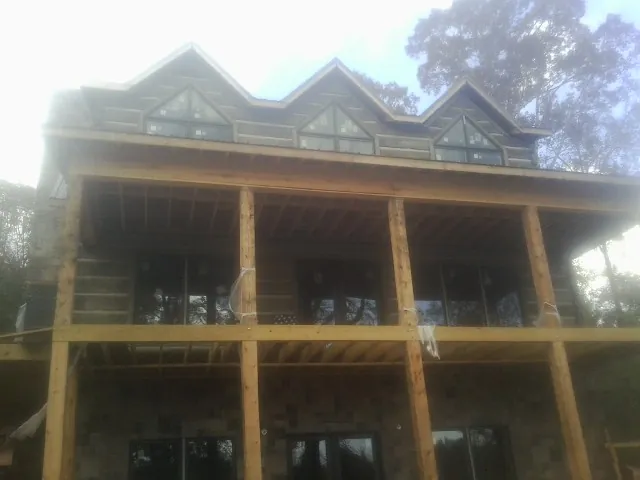 Dormers and porch framing on a large log home under construction — Roof Coating work by our crew in Galway