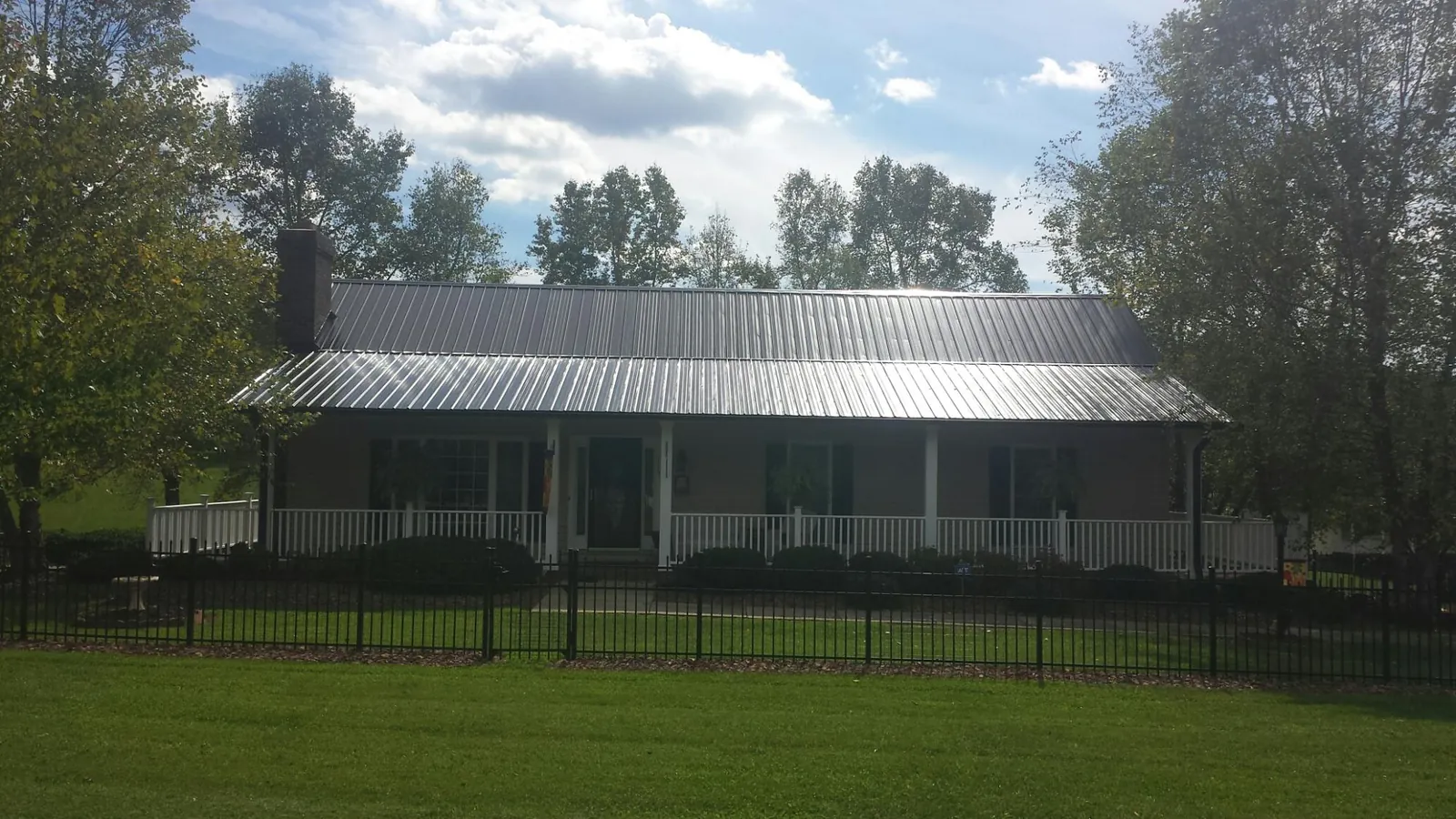 Gray metal roof on a brick ranch with a full width front porch — Gutter Guard Installation work by our crew in Galway