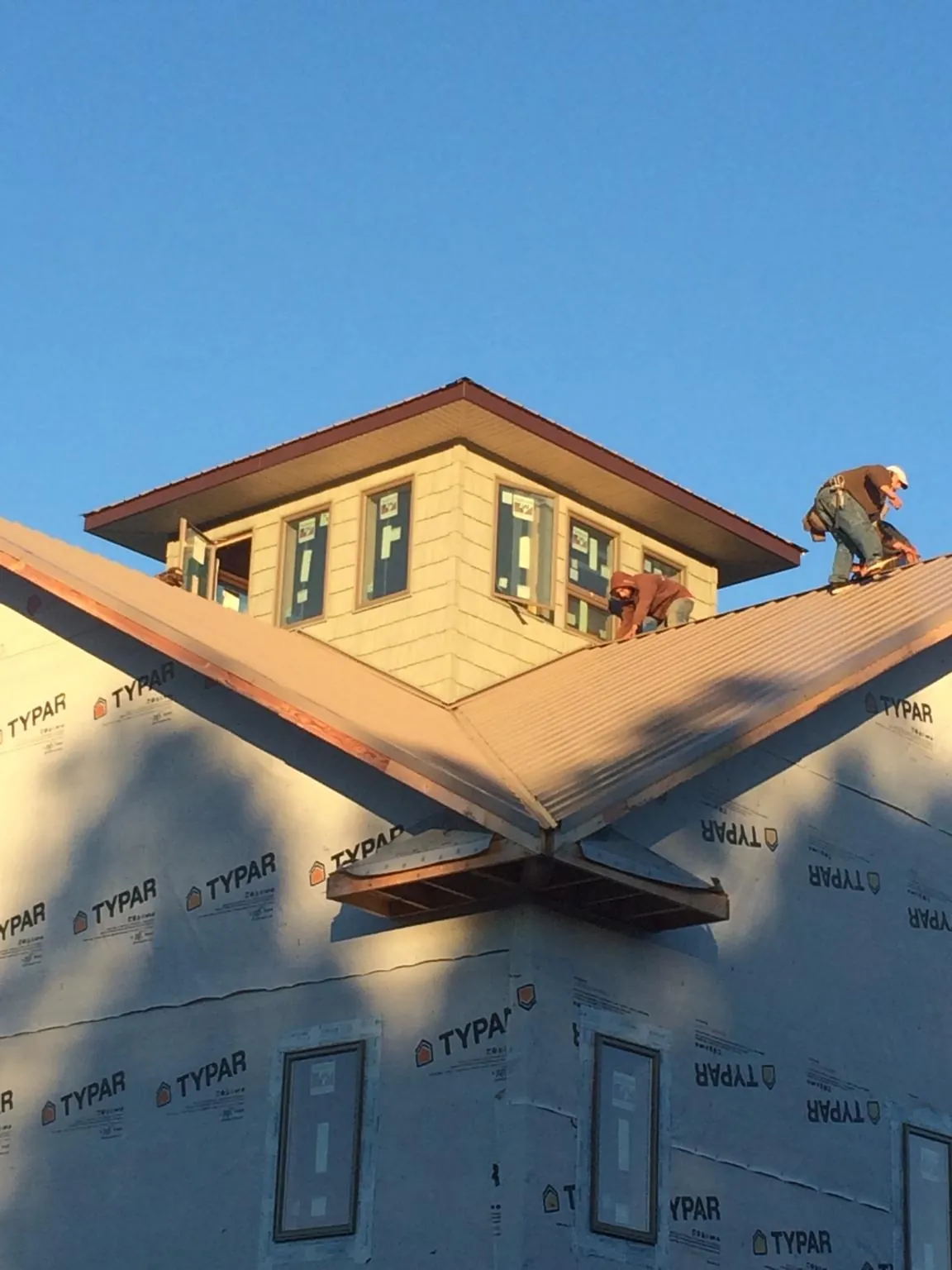 Roofers working around a rooftop cupola on a new metal roof at sunset — Roof Waterproofing in Galway by Roofing Brothers